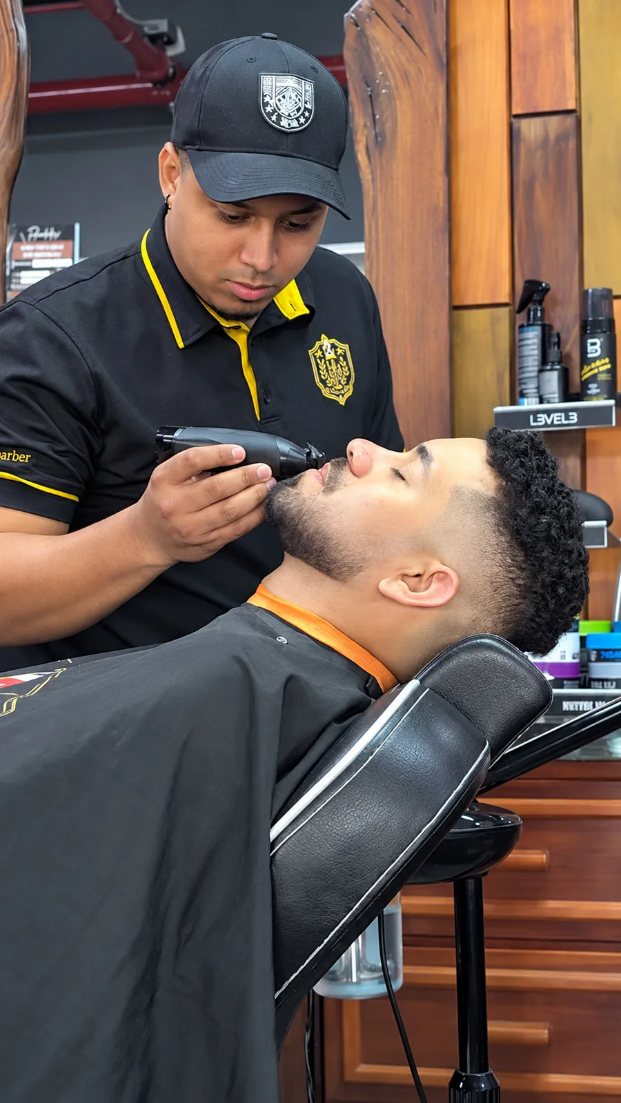 Barbero perfilando la barba de un cliente con máquina