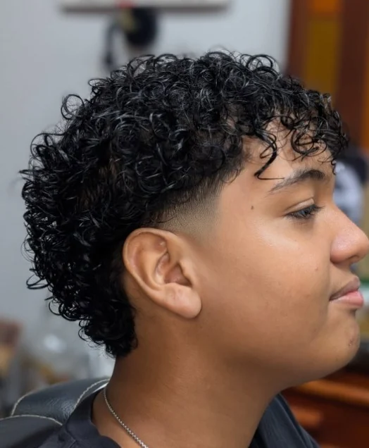 Cliente con cabello rizado definido y degradado lateral, cortado en M&A